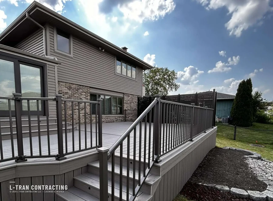 Deck with dark railings against brick and siding home