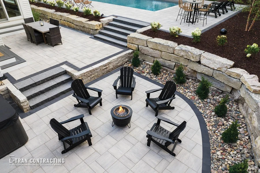 Aerial view of patio with fire pit and stone retaining wall near pool