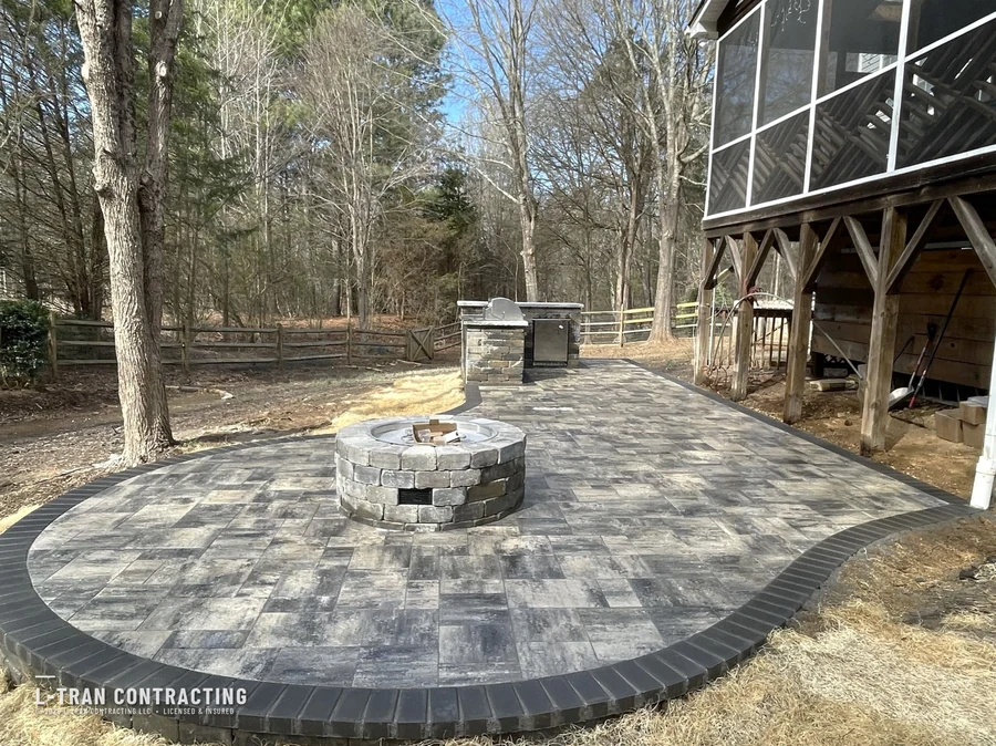 Circular paver patio with stone fire pit and outdoor kitchen