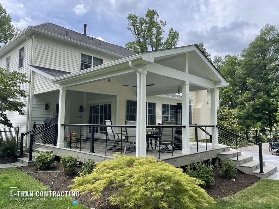 Covered porch with black cable railing and stone chimney