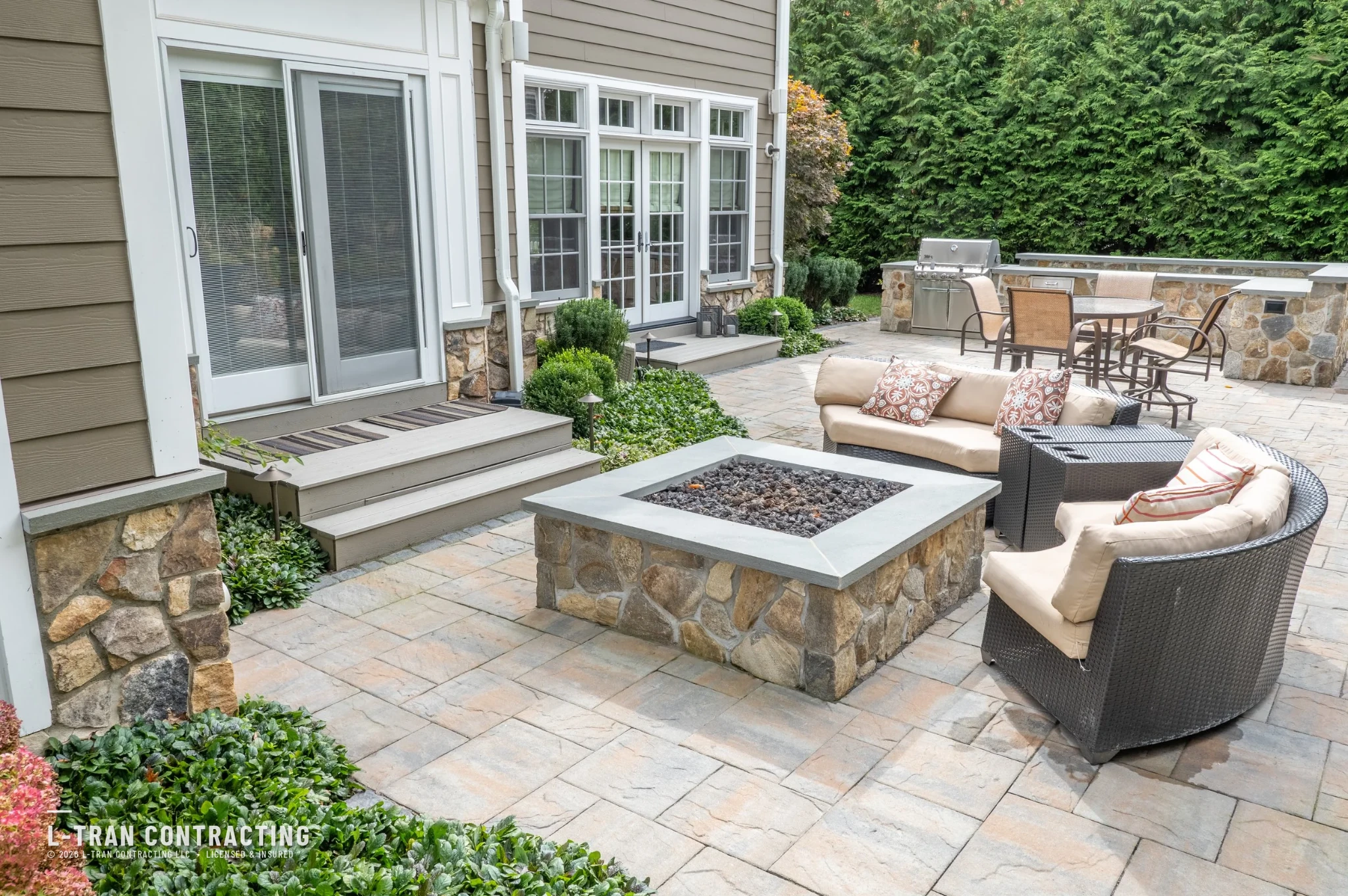 Custom stone patio with built-in fire pit and outdoor seating, built by L-Tran Contracting