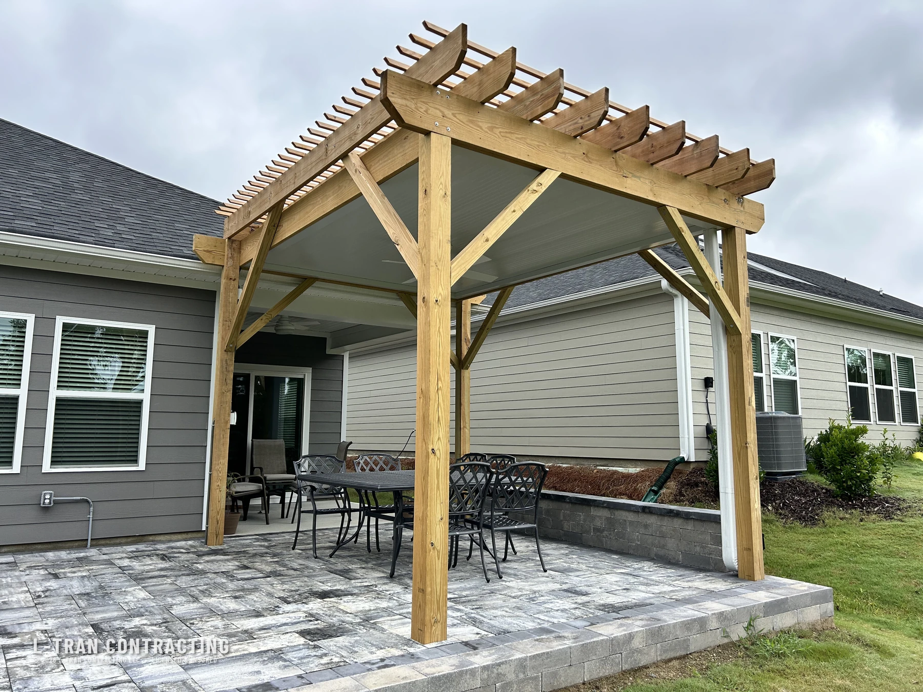 Custom pergola with paver patio and outdoor dining set built by L-Tran Contracting